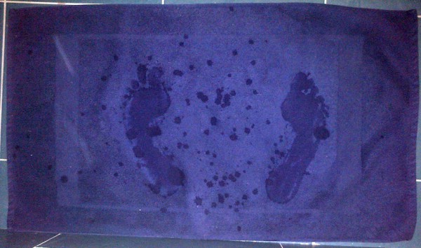 Tapis de bain bleu laissant apparaître l'empreinte humide de deux pieds