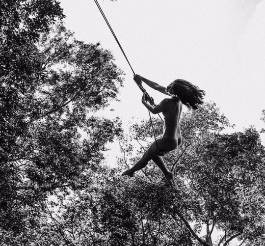 Une femme nue qui jouerait à Tarzan entre les arbres