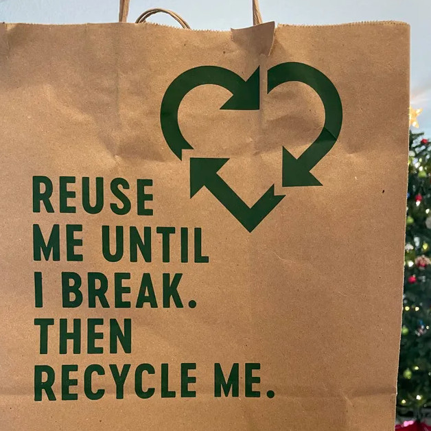 Un sac en papier kraft, sur lequel est inscrite la mention « reuse until I break. Then recycle me. » accompagné d'un logo de recyclage en forme de cœur